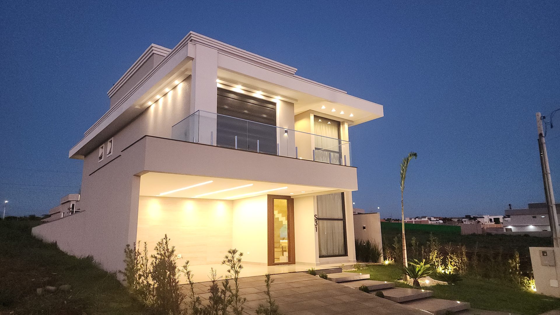 Sobrado 3 suites no Condominio Terras Alpha Cascavel - fachada moderna com iluminacao noturna, sacada em vidro temperado e arquitetura contemporanea