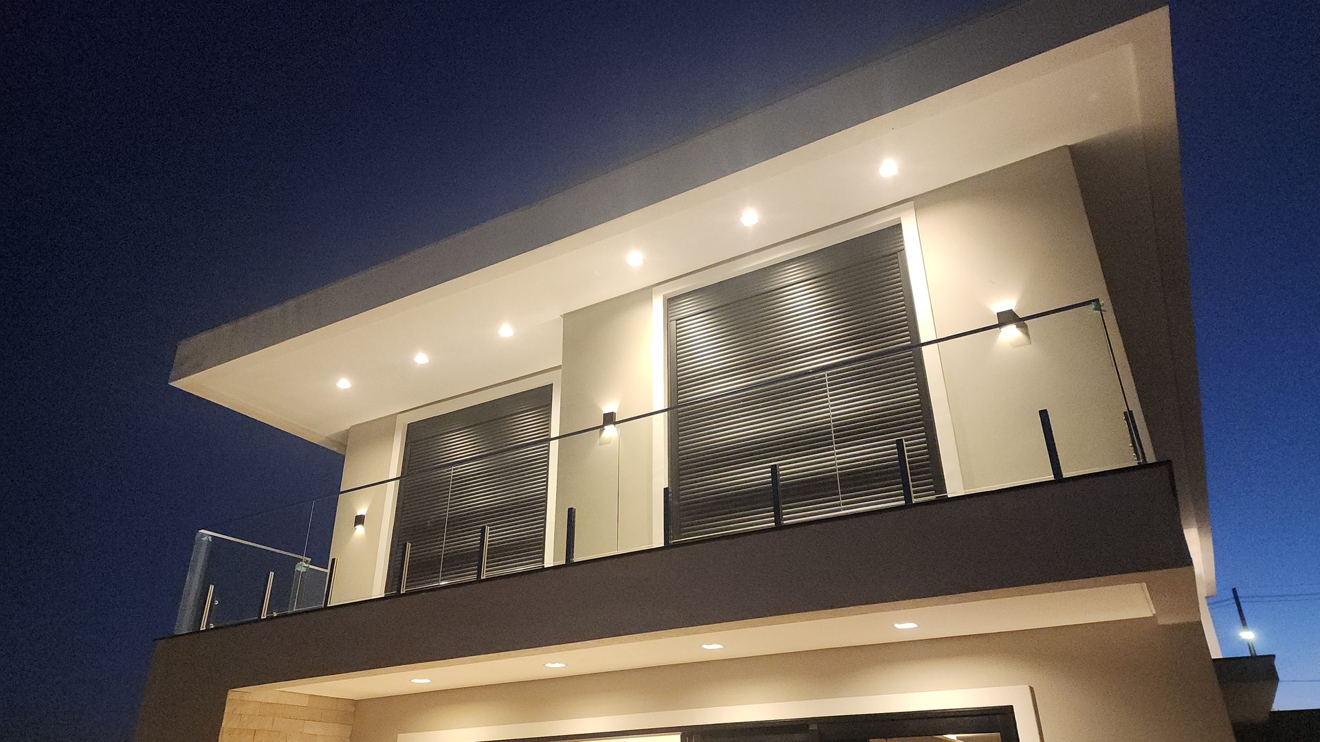 Fachada segundo pavimento com sacada em vidro e persianas integradas no sobrado Terras Alpha