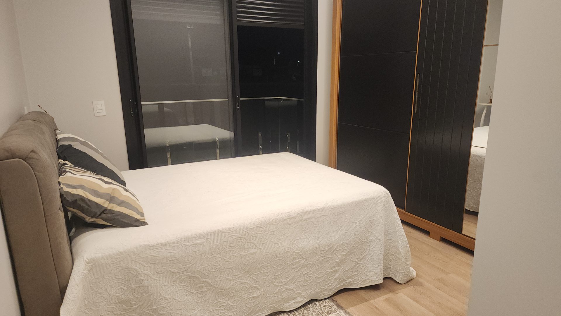Suite com armario preto e madeira planejado e sacada no sobrado Terras Alpha