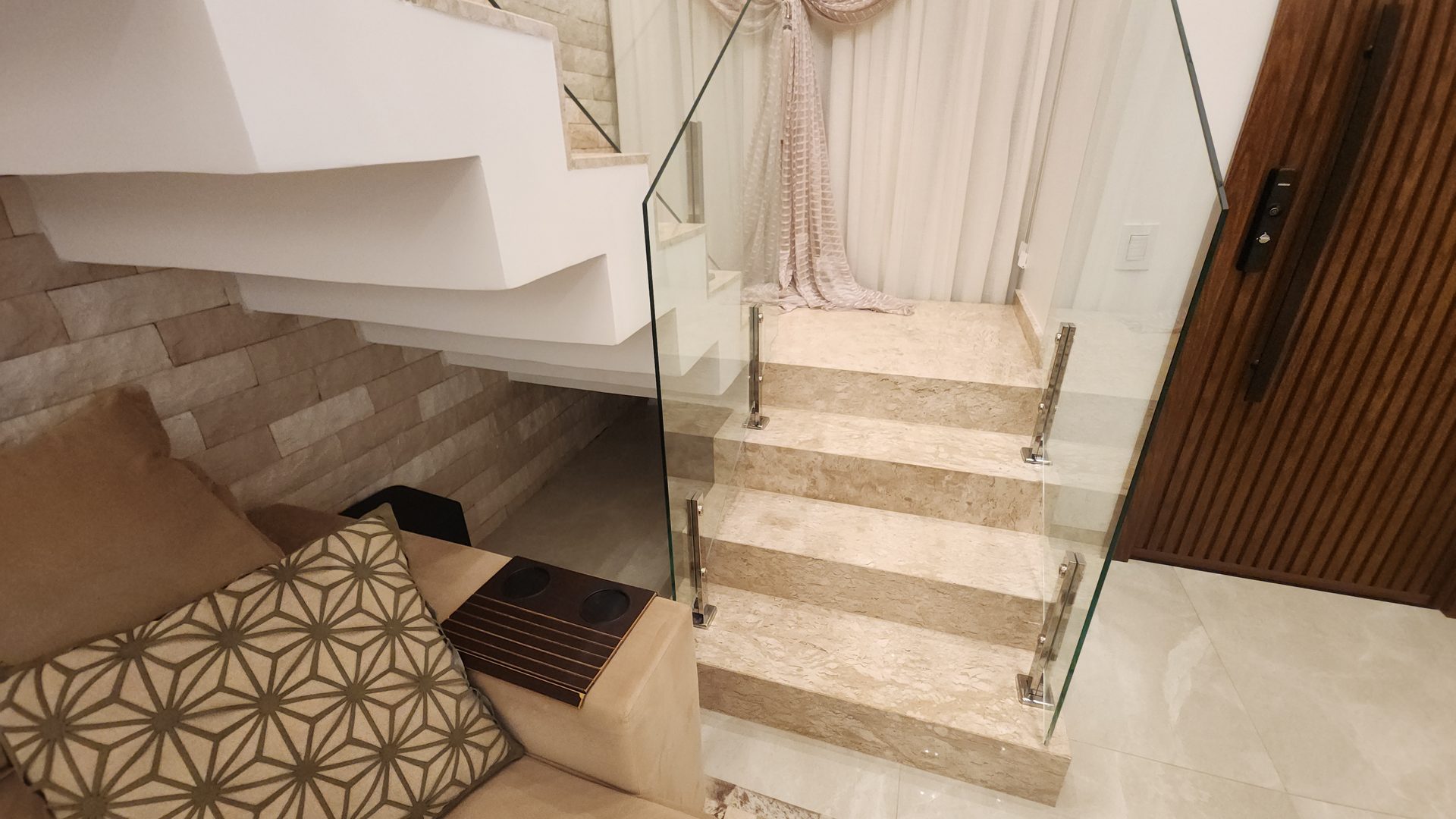 Detalhe da escada em marmore travertino com guarda-corpo em vidro temperado no sobrado Alphaville