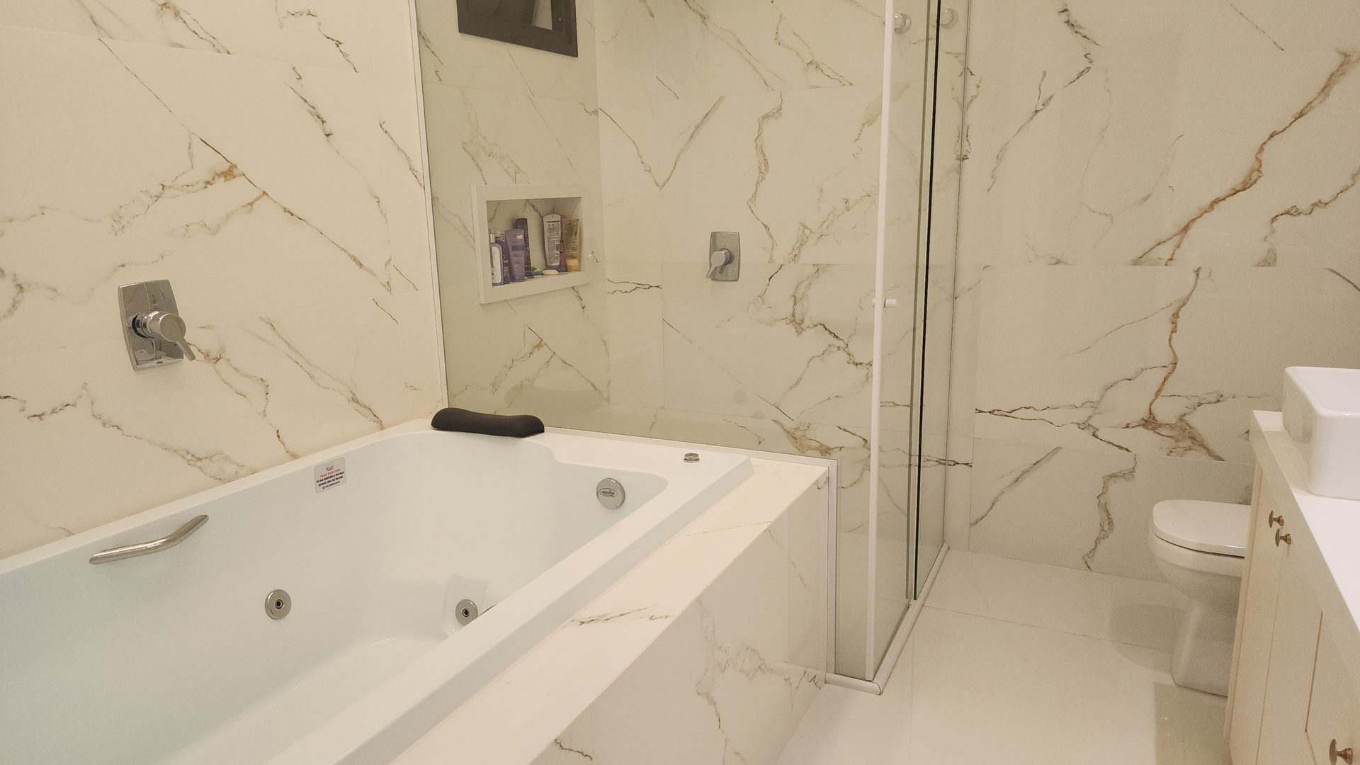 Banheiro suite master com banheira de hidromassagem e porcelanato Calacatta Gold no sobrado Terras Alpha