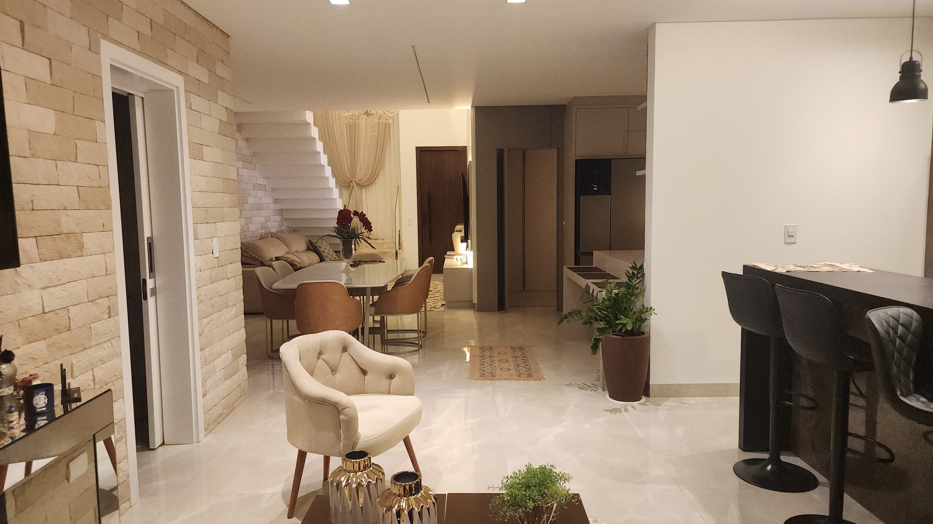 Living integrado com pe direito duplo, escada em marmore e parede canjiquinha no sobrado Terras Alpha