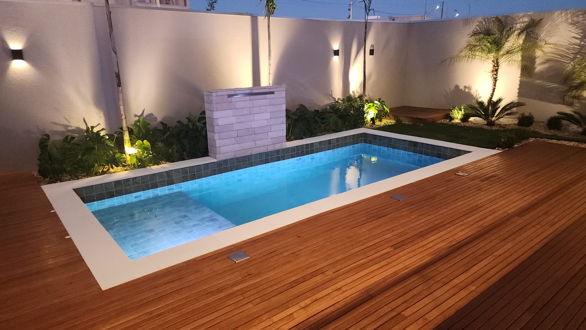 Piscina com deck de madeira nobre e cascata em pedra no sobrado Terras Alpha Cascavel